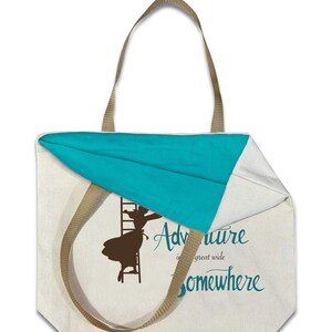 Op de afbeelding: Cr&egrave;mekleurige draagtas met een turquoise binnenkant en bruine bandjes. De tas heeft een silhouet van een persoon die een ladder beklimt, met de woorden "Adventure is a great wide somewhere" in turquoise schrift.