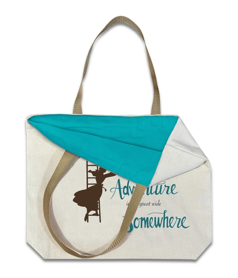 Op de afbeelding: Cr&egrave;mekleurige draagtas met een turquoise binnenkant en bruine bandjes. De tas heeft een silhouet van een persoon die een ladder beklimt, met de woorden "Adventure is a great wide somewhere" in turquoise schrift.