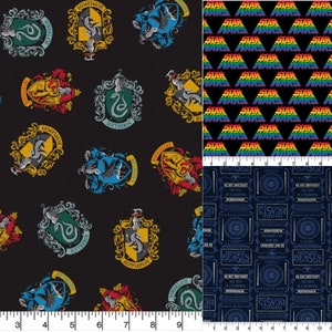 Op de afbeelding: Een zwarte stof met een herhalend patroon van Hogwarts-huiswapens. De wapens zijn in hun traditionele kleuren rood, geel, blauw en groen. De stof ligt naast een zwarte stof met een herhalend patroon van de woorden "Star Wars" in regenboogkleuren. De stof ligt naast een blauwe stof met een herhalend patroon van een Fantastic Beasts and Where to Find Them-logo.