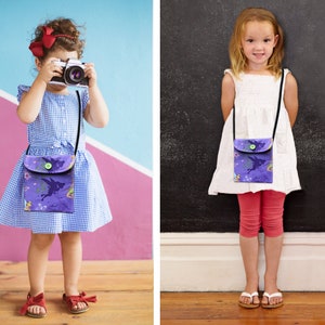 May include: Two children wearing purple and green fairy-themed crossbody bags. The bags have a flap with a button closure and a black adjustable strap.