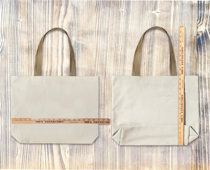 Op de afbeelding: Twee beige canvas draagtassen met bruine handvatten worden getoond tegen een houten achtergrond. Een houten liniaal is op elke tas geplaatst om de afmetingen te meten. De tassen zijn rechthoekig met een eenvoudig ontwerp.