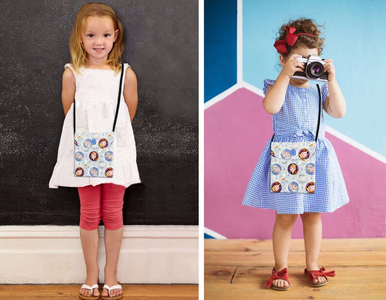 May include: Two children wearing white and blue dresses with a white crossbody bag featuring a cartoon print of two girls. The bag has a black strap. The girl on the left is wearing red pants and white sandals. The girl on the right is holding a camera and wearing red sandals.