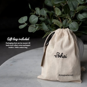 May include: A white cotton drawstring bag with black embroidery that reads "ohsi" and "Kohsipets.com". The bag is sitting on a white surface. Gift bag included. Packaging that can be reused. All leads and collars come packaged inside a 100% cotton bag.