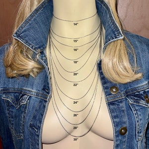 May include: A display of silver chain necklaces of varying lengths, from 14 inches to 30 inches, against a mannequin torso. Each chain is labeled with its length in inches. The mannequin is wearing a denim jacket.