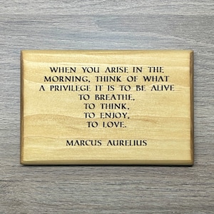 May include: A wooden sign with a quote by Marcus Aurelius that reads: "When you arise in the morning, think of what a privilege it is to be alive to breathe, to think, to enjoy, to love."