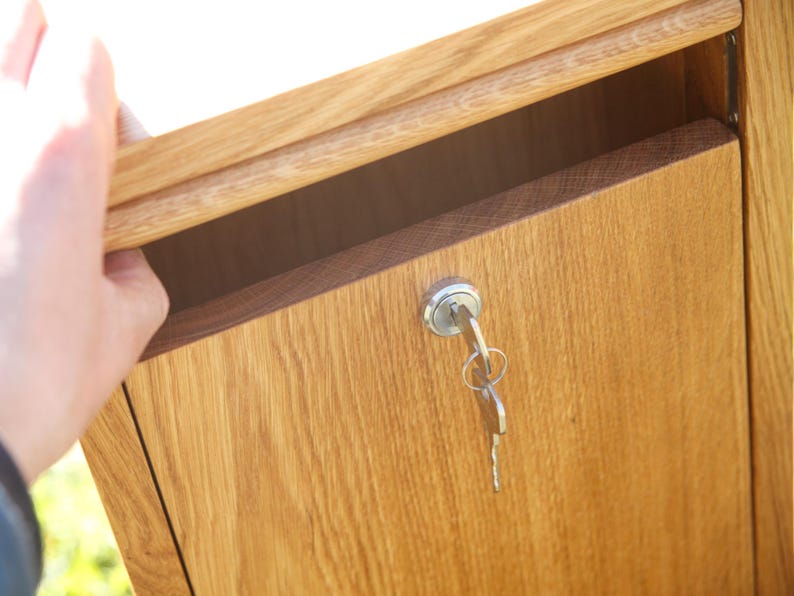 May include: A wooden box with a keyhole and a key in the lock. The box is made of light brown wood and has a natural finish.