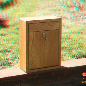 May include: A wooden box with a drawer and a keyhole. The box is light brown and has a wood grain pattern. The box is sitting on a wooden surface.