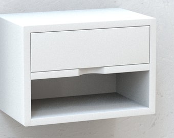 Può includere: Comodino bianco a parete con un cassetto e uno scaffale sotto. Il cassetto ha una maniglia incassata.
