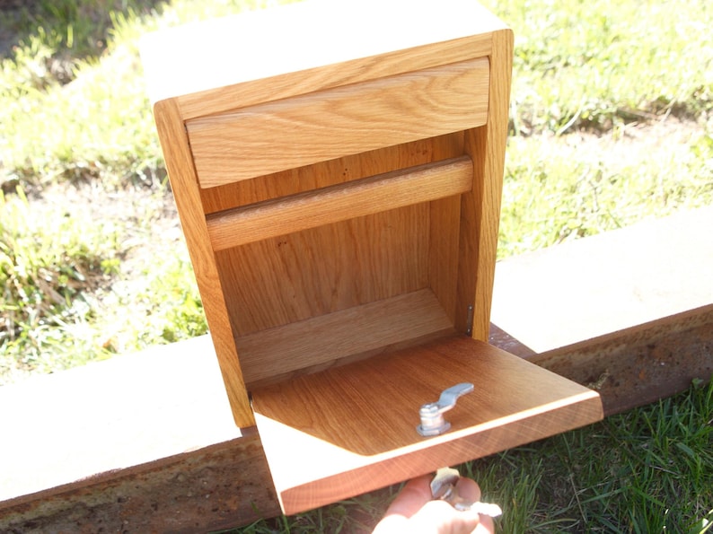 May include: A wooden box with a drawer and a hinged door. The door is open and the inside of the box is visible. The box is made of light wood and has a natural finish.