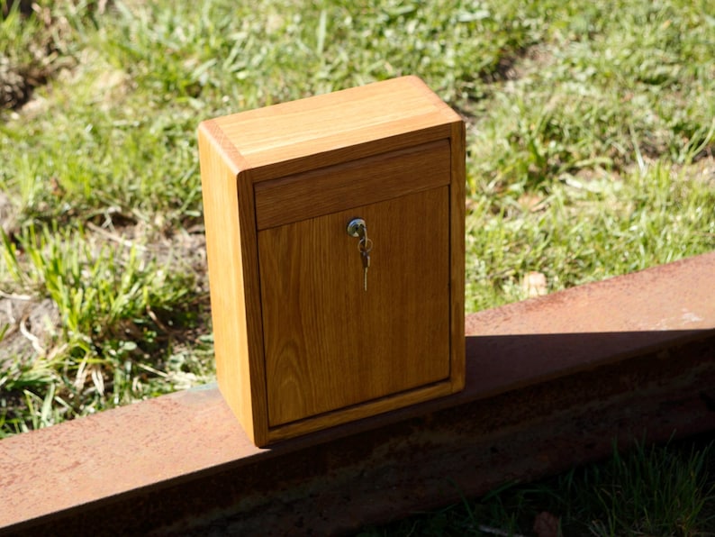 May include: A wooden box with a keyhole and a drawer. The box is made of light brown wood and has a natural wood finish.