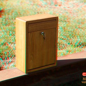 May include: A wooden mailbox with a keyhole and a small drawer. The mailbox is sitting on a brown surface.