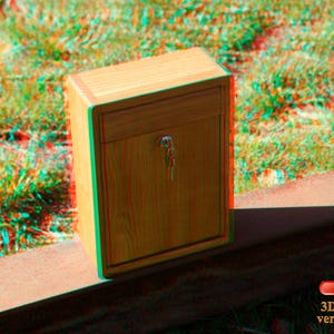 May include: A wooden box with a drawer and a keyhole. The box is sitting on a red surface. The text "3D Brille verwenden" is visible in the lower right corner of the image.
