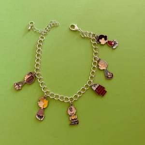 May include: A white ceramic mug with a black handle and the text "But First, Coffee" in a bold, black font. The mug is set against a blurred background, suggesting a cozy setting.