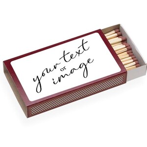 May include: A maroon matchbox with a white rectangular label that reads "your text or image" in black cursive. The box is partially open, revealing several wooden matches with brown tips.