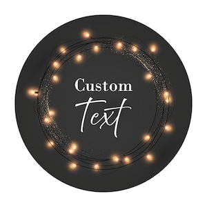 May include: A black circle with a string of warm white lights wrapped around the edge. The lights are glowing and there is a sparkle effect. The text "Custom Text" is in the center of the circle.