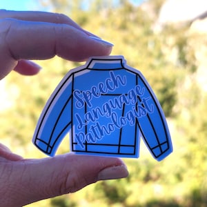 May include: A light blue sticker in the shape of a jacket. The sticker has the words "Speech Language Pathologist" in a cursive font. The jacket design has black outlines and details.