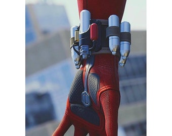 May include: Close-up of a red and black glove with a wrist-mounted device. The glove has a textured surface and a black palm. The wrist device features silver and red cylindrical components, suggesting a high-tech or superhero theme.