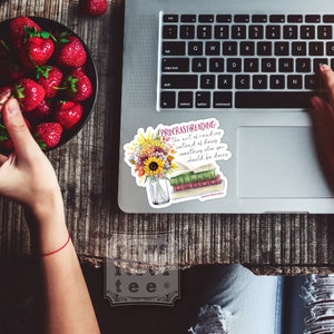 Pu&ograve; includere: Un adesivo in vinile con un bouquet di girasoli e fiori autunnali in un barattolo di vetro accanto a una pila di tre libri. Il testo recita: PROCRASTREADING: the art of reading instead of doing something else you should be doing.