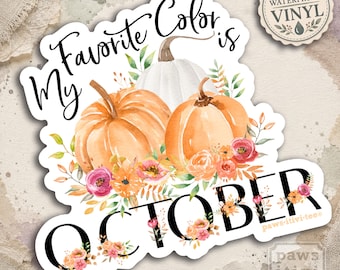 Può includere: Un adesivo in vinile con zucche ad acquerello arancioni e bianche, circondate da fiori arancioni, rosa e gialli e foglie verdi. Il testo recita My Favorite Color is OCTOBER in nero, con la scritta paws-itivee nella parte inferiore.