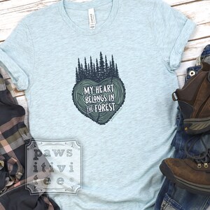 May include: Light blue t-shirt with a forest green tree design and the text "My heart belongs in the forest".