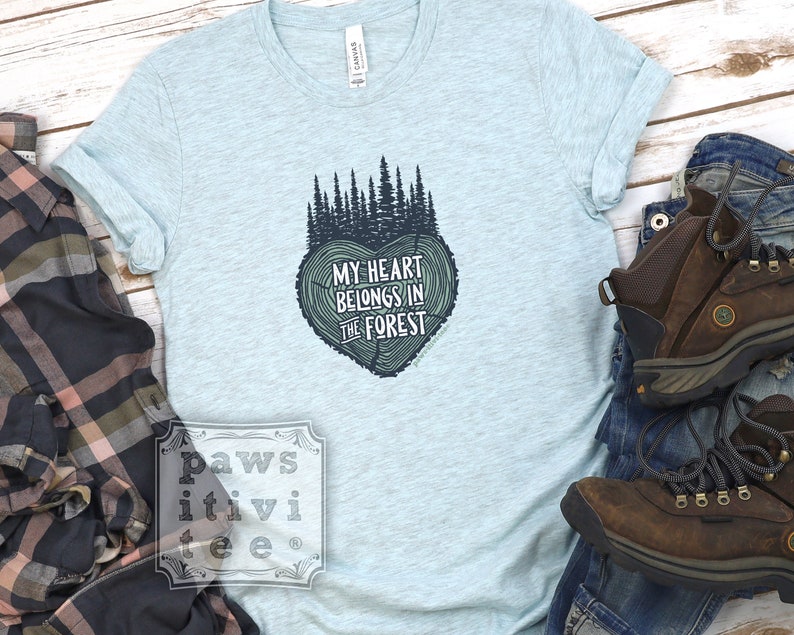 May include: Light blue t-shirt with a forest green tree design and the text "My heart belongs in the forest".