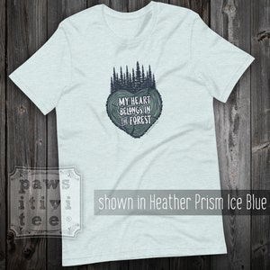May include: Light blue t-shirt with a forest green tree design in the shape of a heart. The text "MY HEART BELONGS IN THE FOREST" is printed inside the heart.