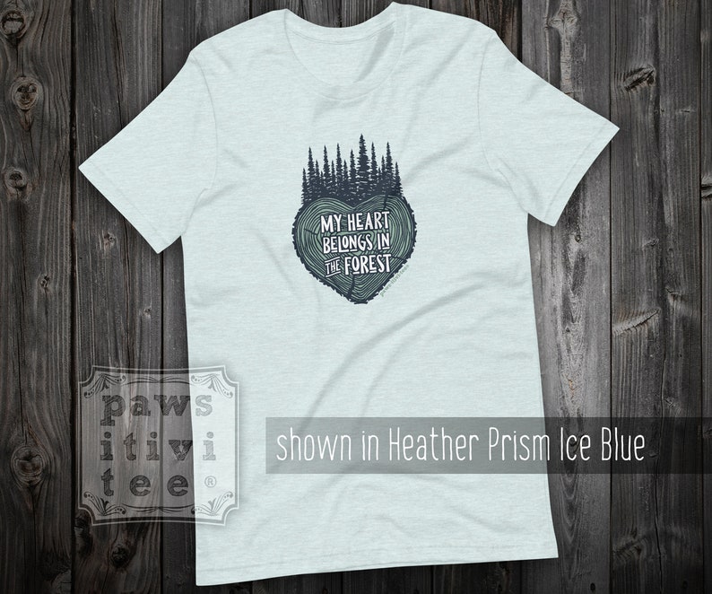 May include: Light blue t-shirt with a forest green tree design in the shape of a heart. The text "MY HEART BELONGS IN THE FOREST" is printed inside the heart.