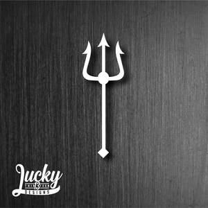 May include: White silhouette of a trident on a dark wood background. The trident has three prongs and a circular center. The text "Lucky Thirteen Designs" is at the bottom of the image.