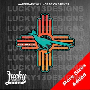 May include: A sticker featuring the state symbol of New Mexico, a roadrunner, inside a stylized Zia symbol. The Zia symbol is a traditional symbol of the Zia Pueblo people and is often used to represent the state of New Mexico. The sticker is orange, yellow, and turquoise.