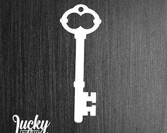 May include: A white silhouette of an old-fashioned key on a dark wood background. The key has a large, ornate head and a long, thin shaft.