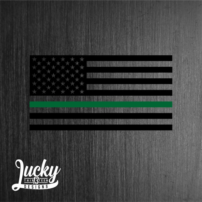 May include: A black and white American flag with a thin green stripe across the middle. The flag is on a textured background.