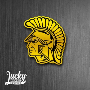 May include: A yellow and black graphic of a Roman soldier wearing a helmet with a plume. The graphic is on a dark wood background.