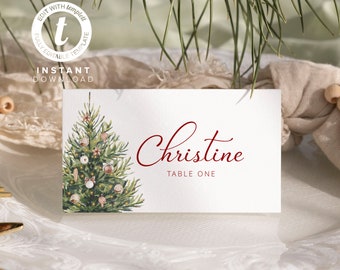 May include: A Christmas-themed place card with a watercolor illustration of a decorated Christmas tree. The name "Christine" is written in red cursive script, followed by "Table One" in smaller red font.