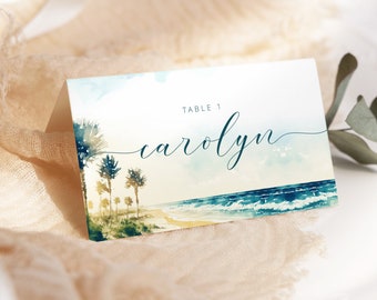 May include: A watercolor beach scene with palm trees and ocean waves. The text "Table 1 carolyn" is printed on the card.