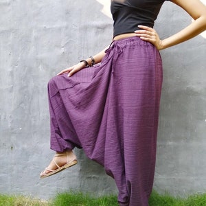 May include: Purple, loose-fitting, wide-leg pants with a drawstring waist. The pants are made of a soft, flowing fabric and have a relaxed, comfortable fit.