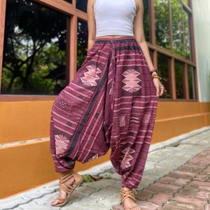 May include: A pair of maroon printed pants with a black waistband and drawstring. The pants have a geometric pattern in shades of pink and black.