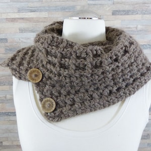 Może przedstawiać: Brązowy komin szydełkowy z dwoma drewnianymi guzikami. Komin wykonany jest z fakturowanym ściegiem.