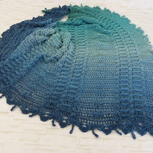 Op de afbeelding: Een gehaakte sjaal in tinten blauw en groen met een gefranst randje.