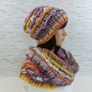 May include: A crocheted hat and matching infinity scarf in a multi-coloured yarn with shades of orange, yellow, purple, and white.