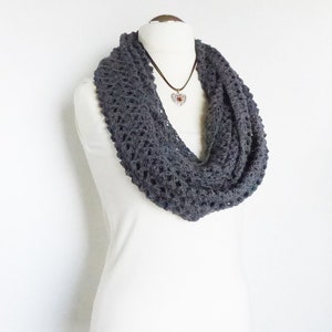 May include: A charcoal grey crocheted infinity scarf. The scarf is made with a delicate open stitch pattern.