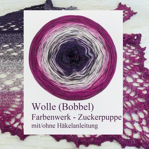Könnte beinhalten: Ein kreisförmiges Garnknäuel mit einem Farbverlauf von Dunkellila in der Mitte bis hin zu Magenta, Grau und Weiß an den Außenrändern. Der Text lautet Wolle (Bobbel) Farbenwerk - Zuckerpuppe mit/ohne Häkelanleitung.