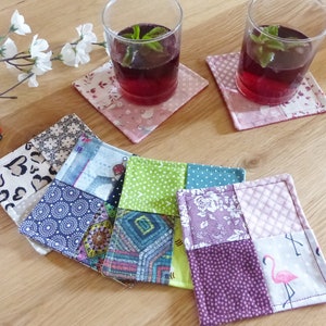 Könnte beinhalten: Sechs bunte Stoffuntersetzer mit Patchwork-Design. Die Untersetzer bestehen aus verschiedenen Stoffen mit verschiedenen Mustern, darunter Herzen, Punkte und geometrische Formen.