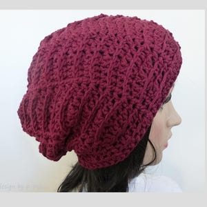 May include: A burgundy crocheted slouchy beanie hat. The hat is made with a textured stitch pattern.
