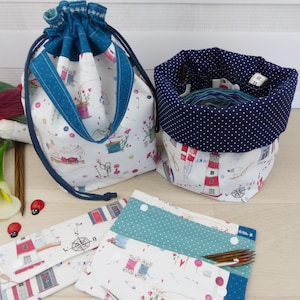 Könnte beinhalten: Ein Stoffbeutel mit Kordelzug und Näh-Motiv, ein Stoff-Eimerbeutel mit nautischem Leuchtturm-Druck und marineblauem Punktfutter sowie zwei flache Stofftaschen mit Druckknöpfen und passenden Leuchtturm- und Näh-Mustern.