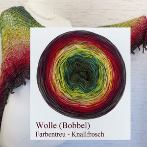 Könnte beinhalten: Ein kreisförmiges Garnknäuel mit einem Farbverlauf von Dunkelgrün und Türkis in der Mitte bis hin zu Gelb, Orange und Dunkelrot an den Außenrändern. Der Text lautet Wolle (Bobbel) Farbentreu - Knallfrosch. Ein gehäkeltes Schultertuch.