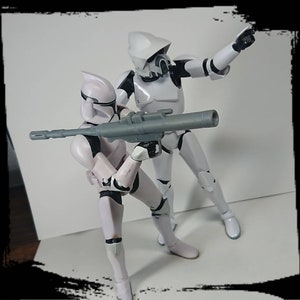 May include: Two white action figures of Star Wars clone troopers. One is holding a blaster rifle and the other is pointing a blaster pistol.