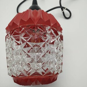 Puede incluir: L&aacute;mpara colgante vintage con una parte superior roja geom&eacute;trica y una pantalla de cristal transparente con dise&ntilde;o de diamantes. La l&aacute;mpara tiene un cable negro y est&aacute; dise&ntilde;ada para colgar. Dise&ntilde;o retro y decorativo.