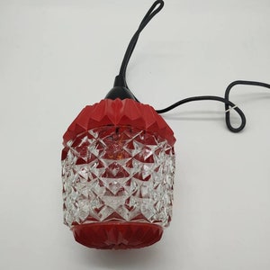 Puede incluir: Una l&aacute;mpara colgante vintage de vidrio rojo y transparente con un dise&ntilde;o facetado. La l&aacute;mpara tiene una parte superior e inferior rojas, con un cuerpo de vidrio transparente con dise&ntilde;o de diamantes. Un cable y un lazo negros est&aacute;n adjuntos para colgar.