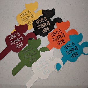 May include: Six colorful paper cutouts shaped like a Mickey Mouse head with the text "Have a magical day!" on each cutout.