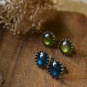 May include: A pair of earrings with a silver setting and iridescent green and blue stones.